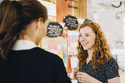 Smiling businesswoman discussing with female colleagues at creative office