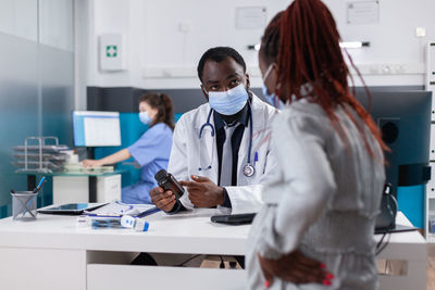 Doctor wearing mask prescribing medicine to patient