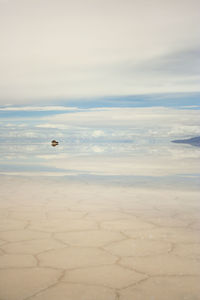 Vehicle with reflection of clouds at salar de uyuni