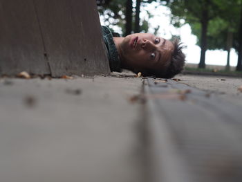 Portrait of surprised young man lying on street