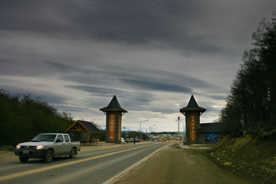 Cars on road by trees against sky in city