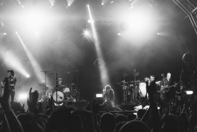 Spectators looking at musicians performing on stage during concert