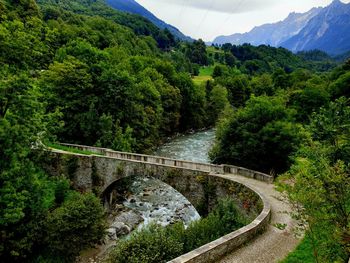 Bridge over road amidst trees against mountains