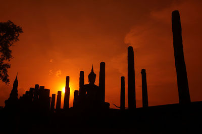 Low angle view of silhouette building against dramatic sky during sunset