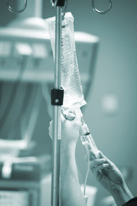 Cropped hands of doctor injecting in iv drip in hospital