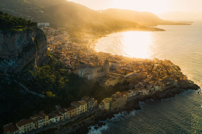 High angle view of sea and buildings against sky at sunset