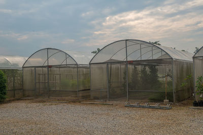 View of abandoned greenhouse against cloudy sky