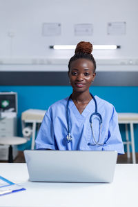 Portrait of young woman using mobile phone in office