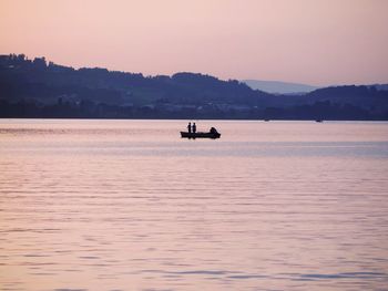 Silhouette boat sailing on sea against sky during sunset