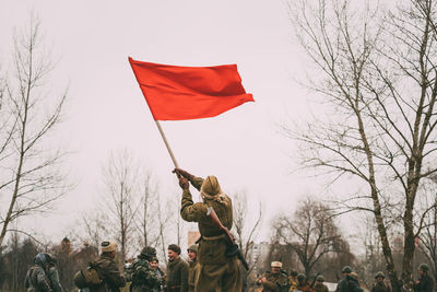 Low angle view of men flag amidst trees against sky