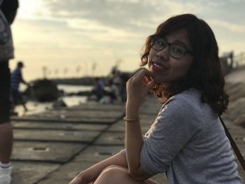 Side view portrait of woman sitting at beach during sunset