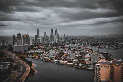 Aerial view of buildings in city against cloudy sky