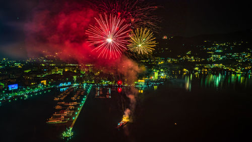 Firework display over illuminated city against sky at night
