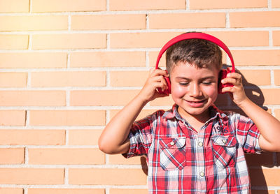 Portrait kid listening to music with headphones on brick wall person