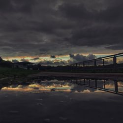 Bridge over river against cloudy sky during sunset