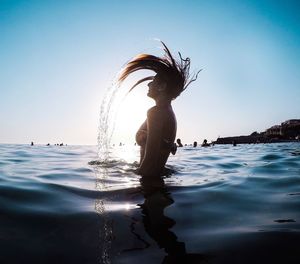 Woman swimming in sea against clear sky