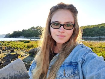 Portrait of smiling young woman against sky