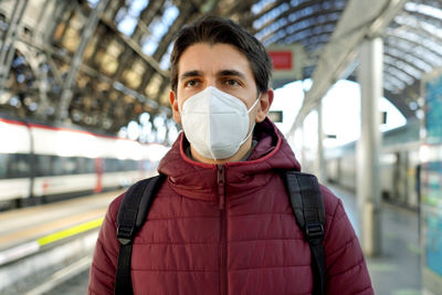 Man wearing mask standing on railroad station