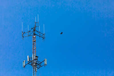 Low angle view of communications tower against blue sky