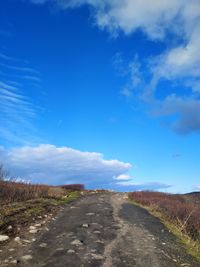 Road along countryside landscape against blue sky