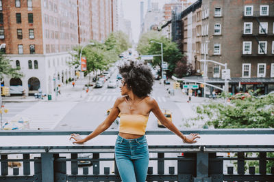 Full length of woman standing on street against buildings in city