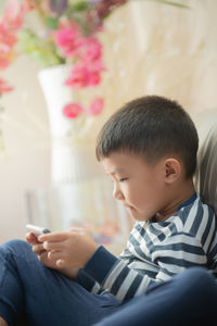 Boy using phone while sitting on sofa at home