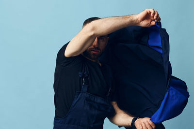 Midsection of man standing against blue background