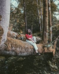 Man sitting on rock in forest