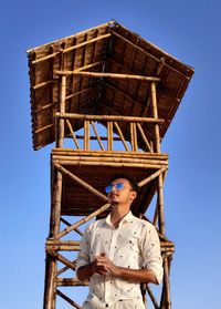 Low angle view of man standing against clear blue sky