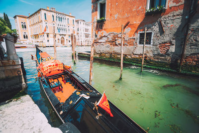 Gondola moored in canal against buildings