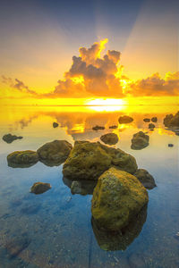 Rocks at sea shore against sky during sunset