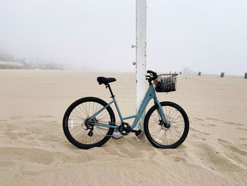 Bicycle parked on sand against clear sky