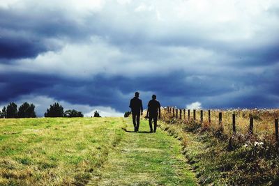 Men walking on field against sky