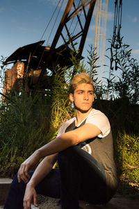 Portrait of young man sitting against plants