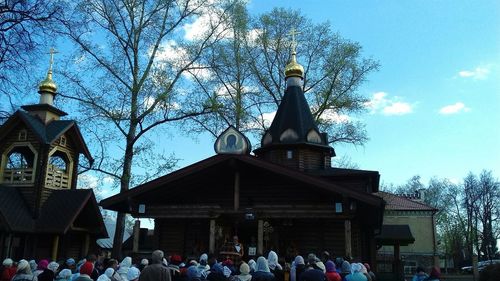 People outside temple against sky