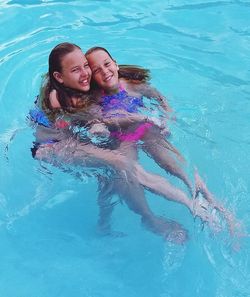 Portrait of sisters swimming pool