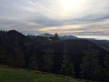 Houses on field against cloudy sky