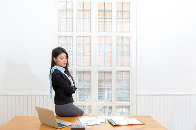 Side view of a young woman sitting on table