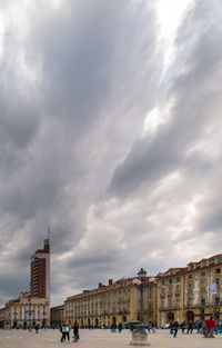 People in city against cloudy sky