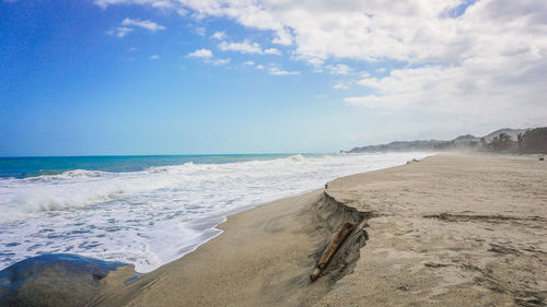 Empty beach against cloudy sky