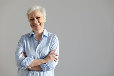 Portrait of doctor standing against gray background