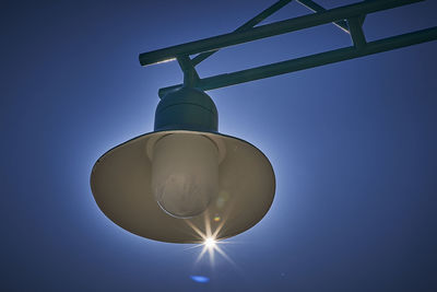 Low angle view of electric lamp against blue sky