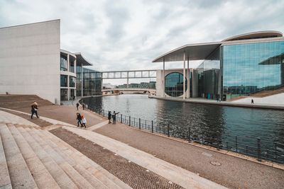 People on modern building in city against sky