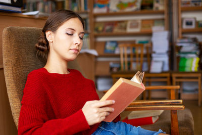 University library beautiful caucasian girl sitting in chair next to bookshelf