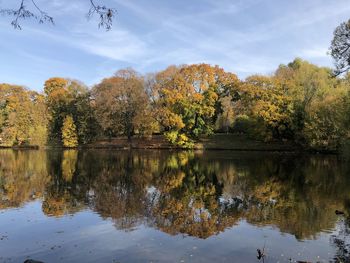 Trees by lake against sky during autumn