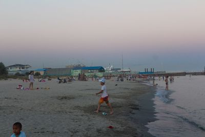 People on beach against sky during sunset