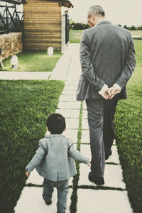 Rear view of father and son walking on grass