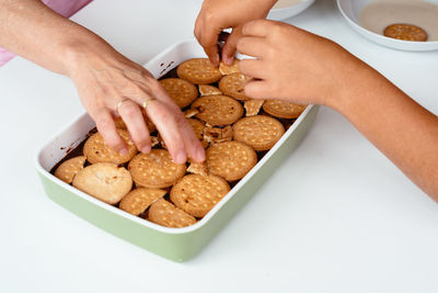 Cropped image of friends having cookies in container on table