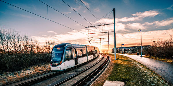 Train on railroad tracks against sky during sunset