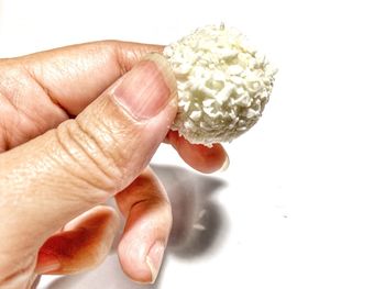 Close-up of hand holding ice cream over white background